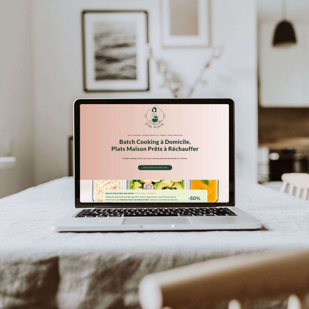 Ordinateur portable sur table avec chaise en premier plan et cadres décoratifs en arrière plan