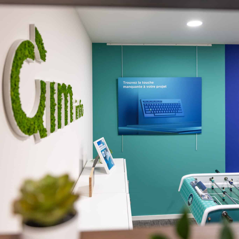 Rédaction-web-qim-info Accueil des bureaux Qim info avec logo végétal, slogan 'Trouvez la touche manquante à votre projet' et baby-foot, reflétant une ambiance professionnelle et conviviale à Genève